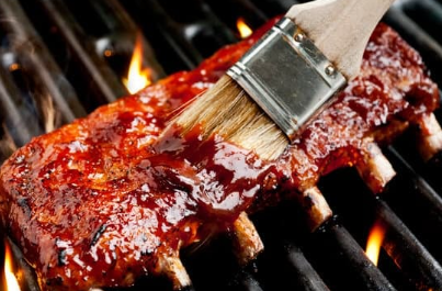 photo of ribs on the grill being sauced