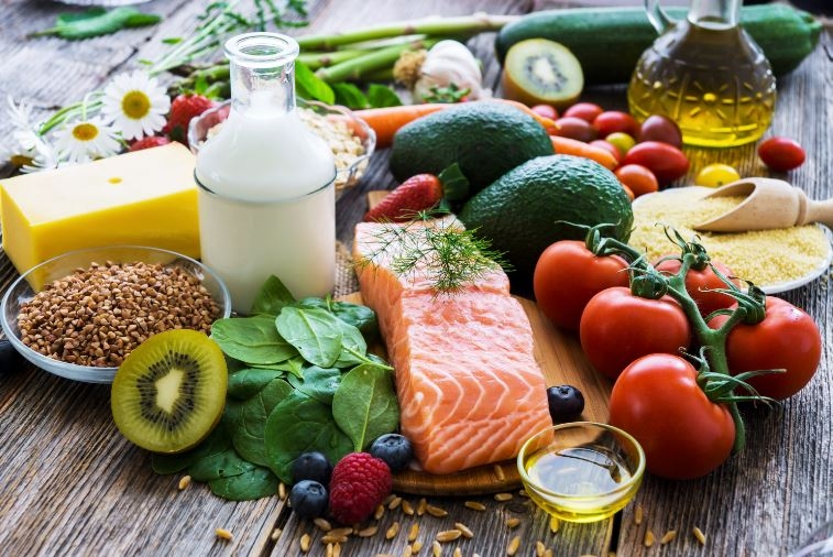 photo of a pile of healthy foods like salmon, avocado, spinach, kiwi, etcetera