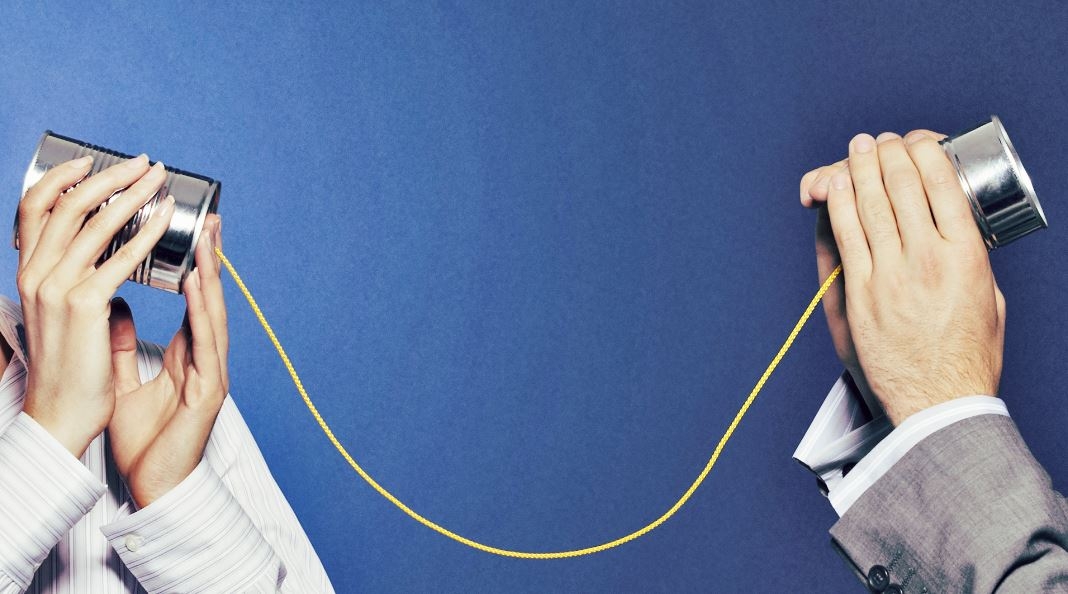 two people holding tin cans attached by string